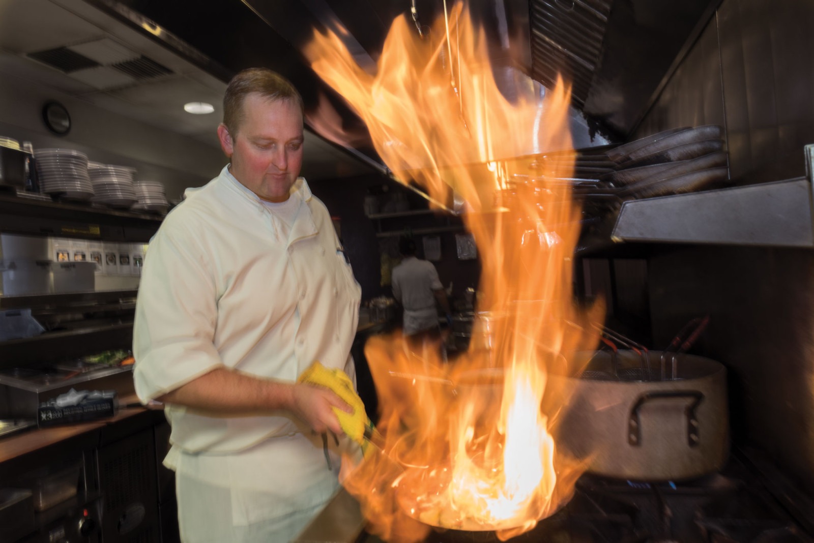 professional chef in the kitchen cooking a meal with a flaming wok